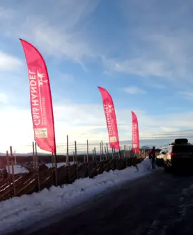 Beachflagg montert ved et tradisjonelt tregjerde på en snødekt fjelltopp.