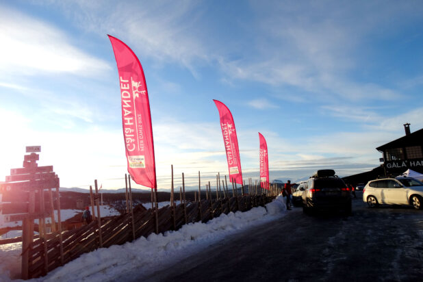 Profileringsflagg montert ved et tradisjonelt tregjerde på en snødekt fjelltopp.