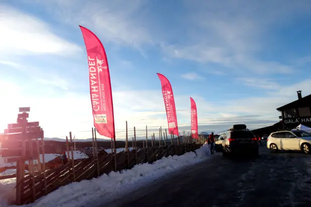 Beachflagg montert ved et tradisjonelt tregjerde på en snødekt fjelltopp.