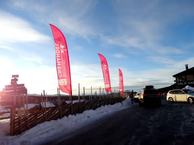 Beachflagg montert ved et tradisjonelt tregjerde på en snødekt fjelltopp.