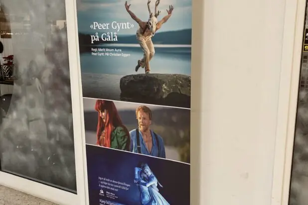 En rollup-banner står på gulvet og viser reklame for Peer Gynt på Gålå med flere bilder fra forestillingen.