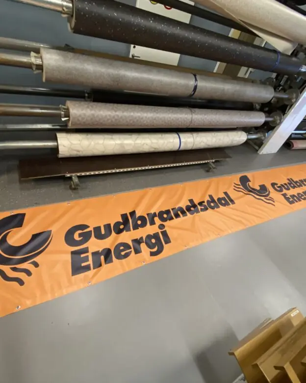 Oransje banner med logoen til Gudbrandsdal Energi ferdig produsert i verkstedet