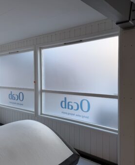 Store vinduer med frostet vindusdekor og logo