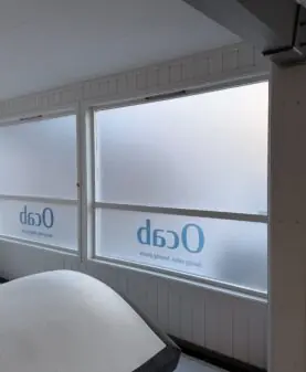Store vinduer med frostet vindusdekor og logo