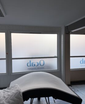 Store vinduer med frostet vindusdekor og logo