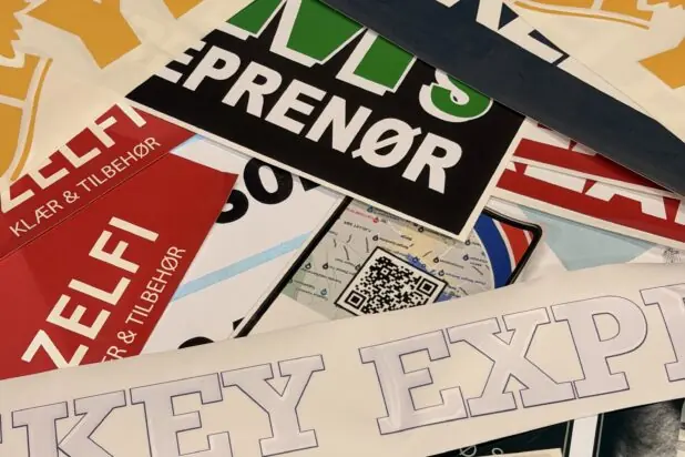 En haug med fargerike klistremerker med ulike tekster og logoer ligger spredt over hverandre.