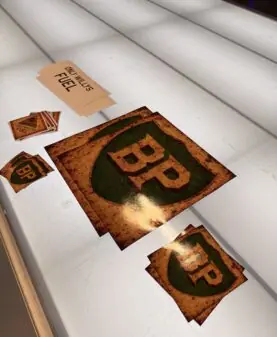 Vintage klistremerker med BP-logo og et ark med teksten Only Bullets Fuel ligger på en lysende overflate.
