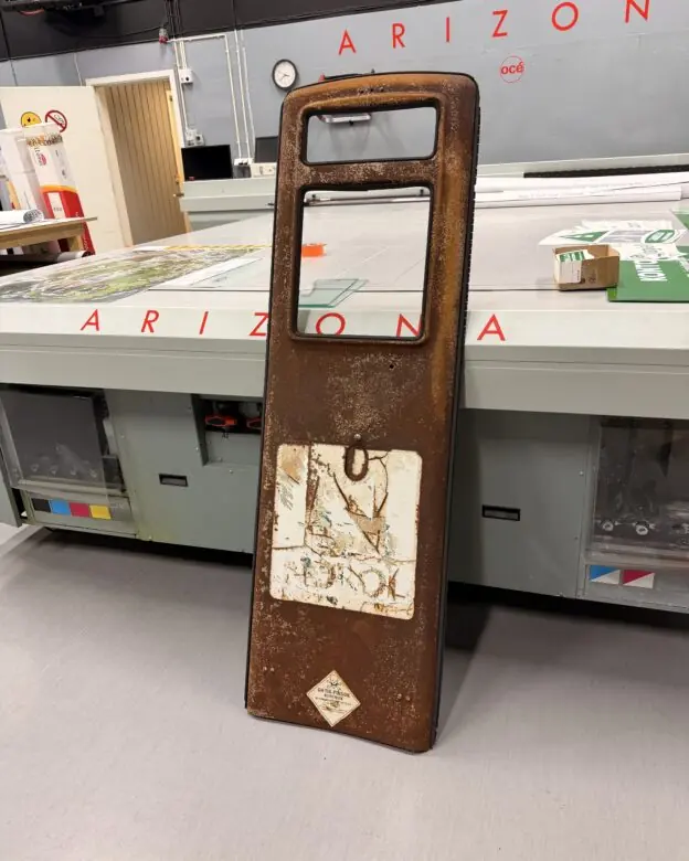 Gamle klistremerker med teksten NEGROC og et diamantformet symbol sitter på et rustent metallpanel.