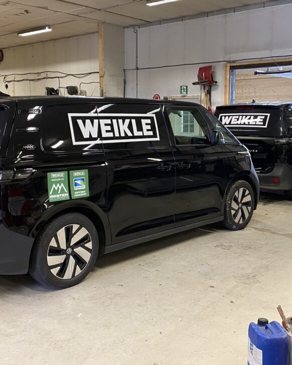 Sort varebil med hvit logo på siden, profesjonelt montert.