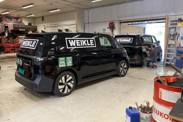 Sort varebil med hvit logo på siden, profesjonelt montert.