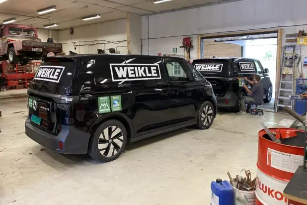 Sort varebil med hvit logo på siden, profesjonelt montert.