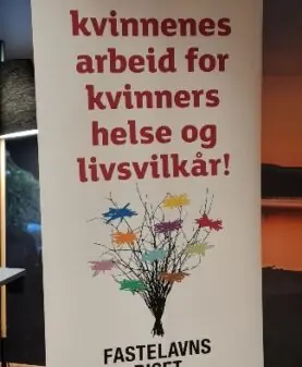 En hvit rollup med rød tekst som oppfordrer til å støtte Sanitetens arbeid for kvinners helse og livsvilkår.